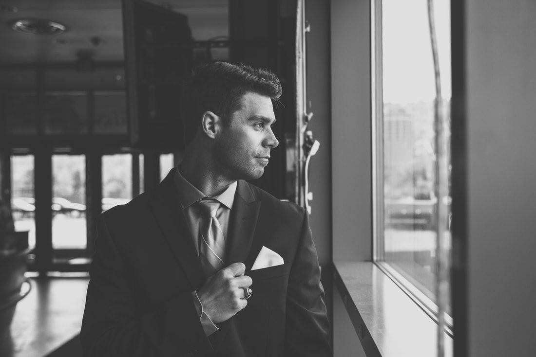 A man in a suit and tie is looking out of a window.