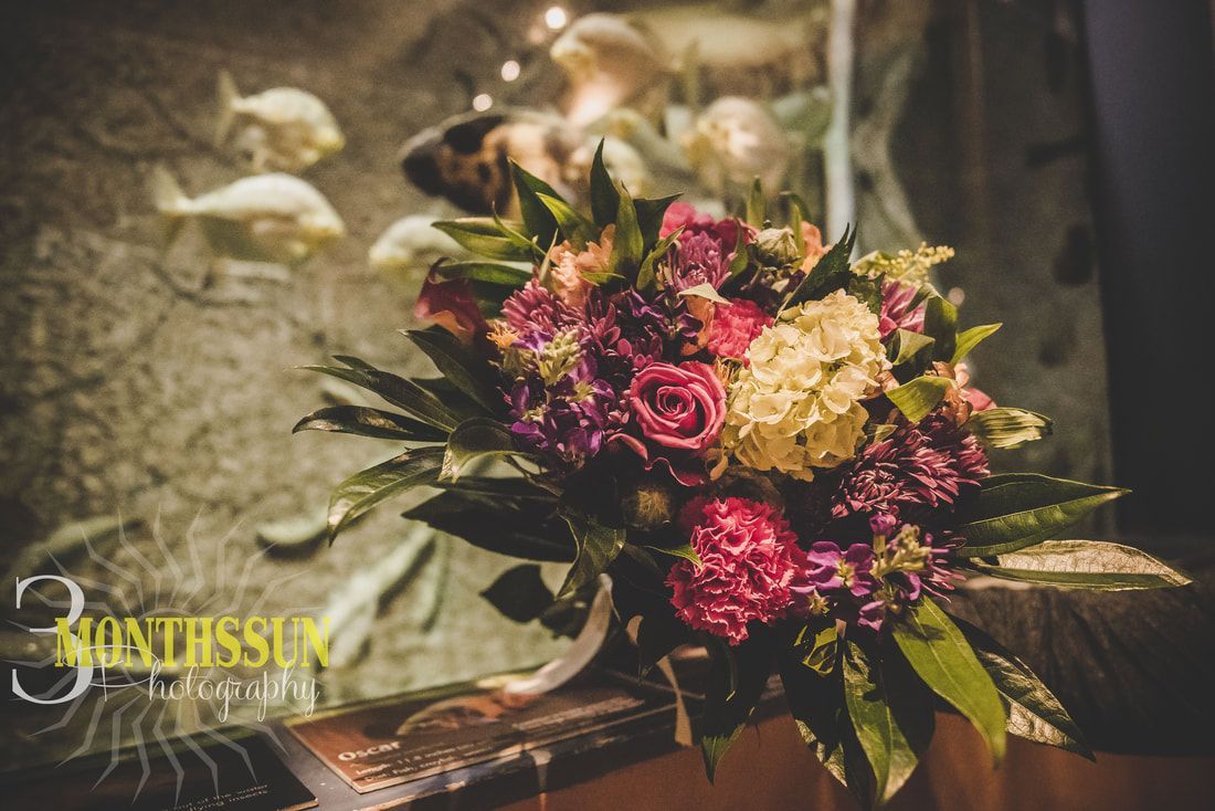 A bouquet of flowers is sitting on a table in front of a fish tank.