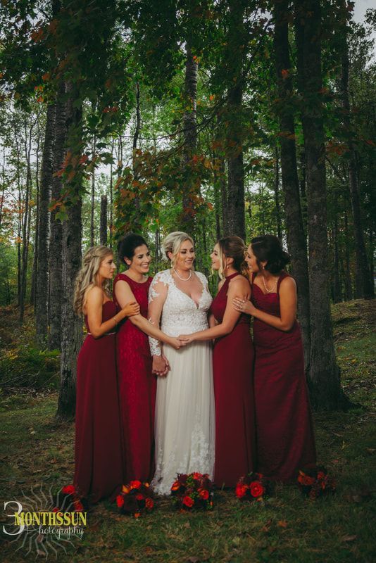 A bride and her bridesmaids are posing for a picture in the woods.