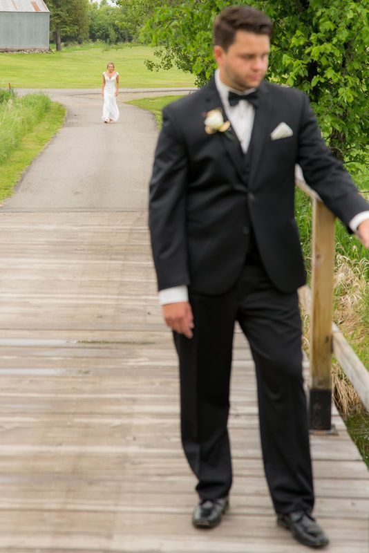 A bride and groom are standing on a wooden bridge.