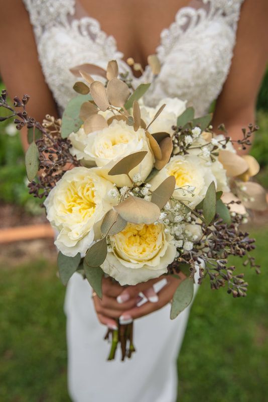 A bride in a white dress is holding a bouquet of white flowers.
