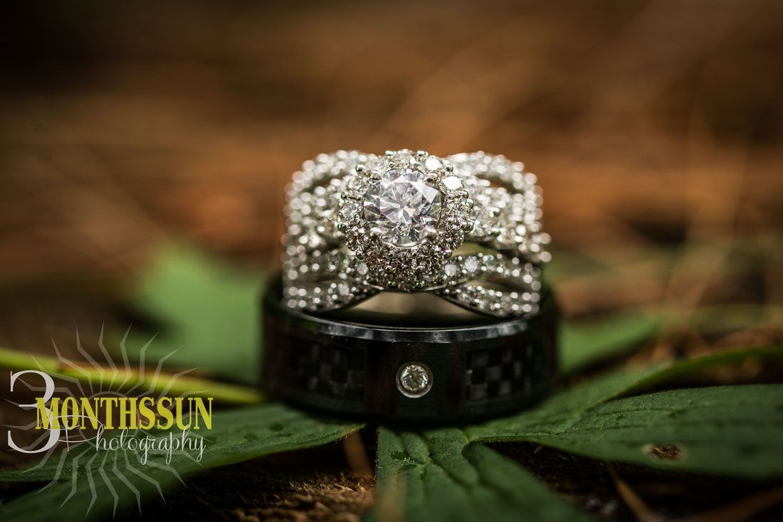 A couple of wedding rings sitting on top of a green leaf.