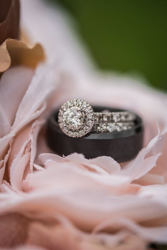 A bride and groom 's wedding rings are sitting on top of a pink flower.