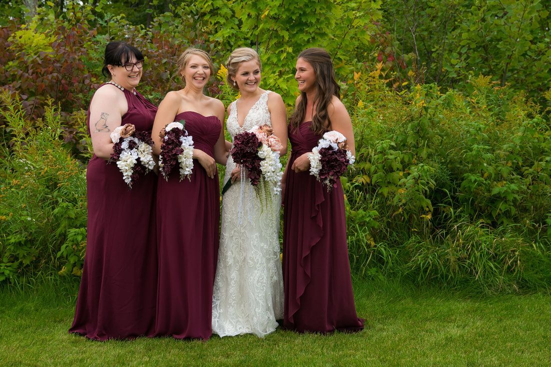 A bride and her bridesmaids are posing for a picture in the grass.