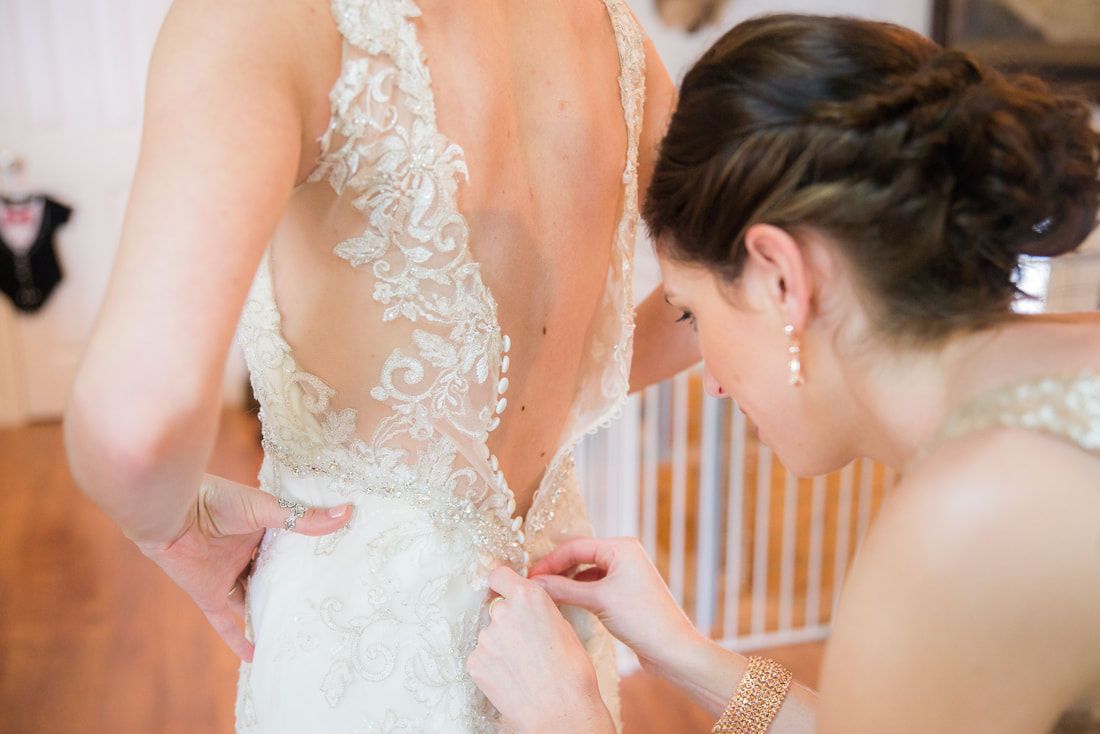 A woman is helping a bride with her wedding dress.