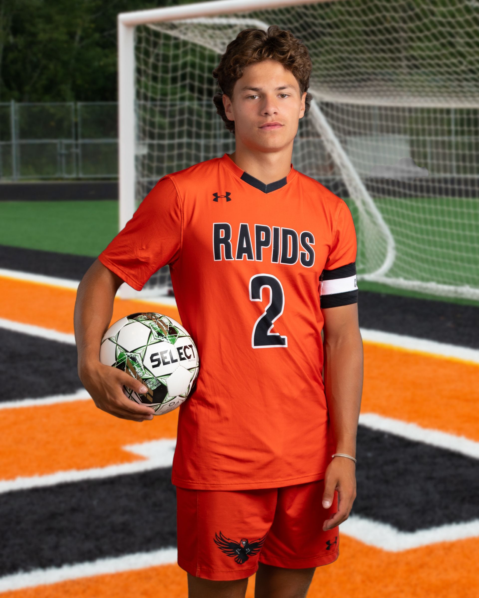 A young man in a rapids jersey is holding a soccer ball