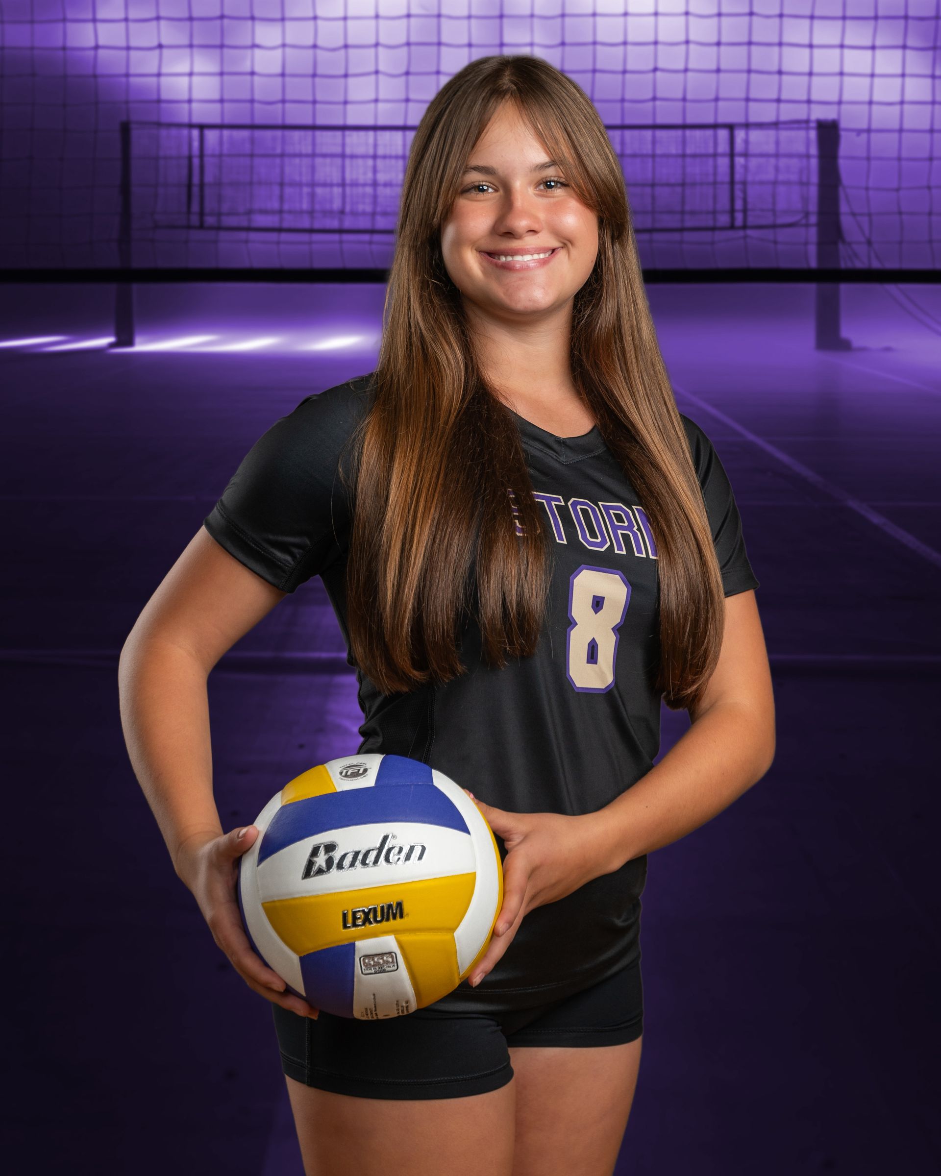 A girl is holding a volleyball in front of a volleyball net.