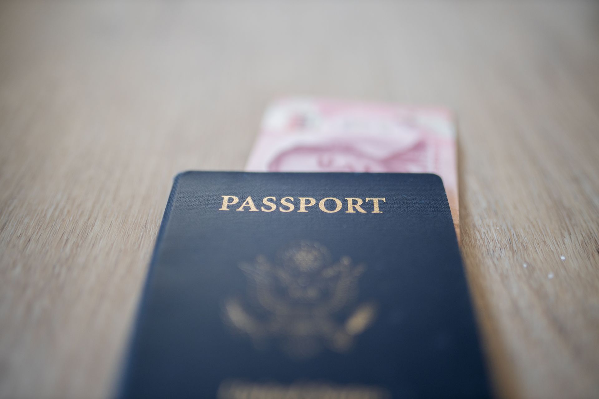 A close up of a passport and a credit card on a wooden table.