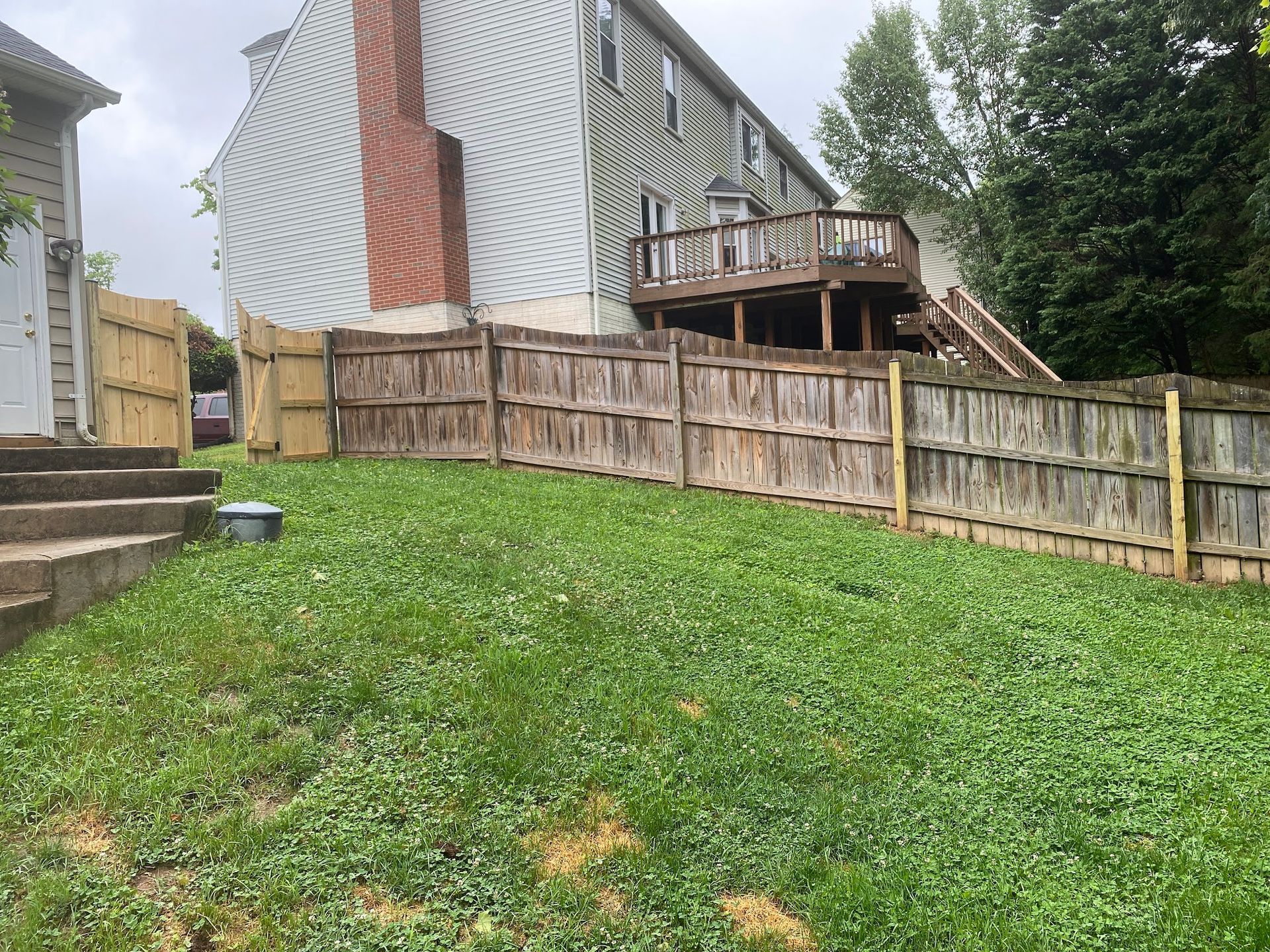 There is a wooden fence in the backyard of a house.