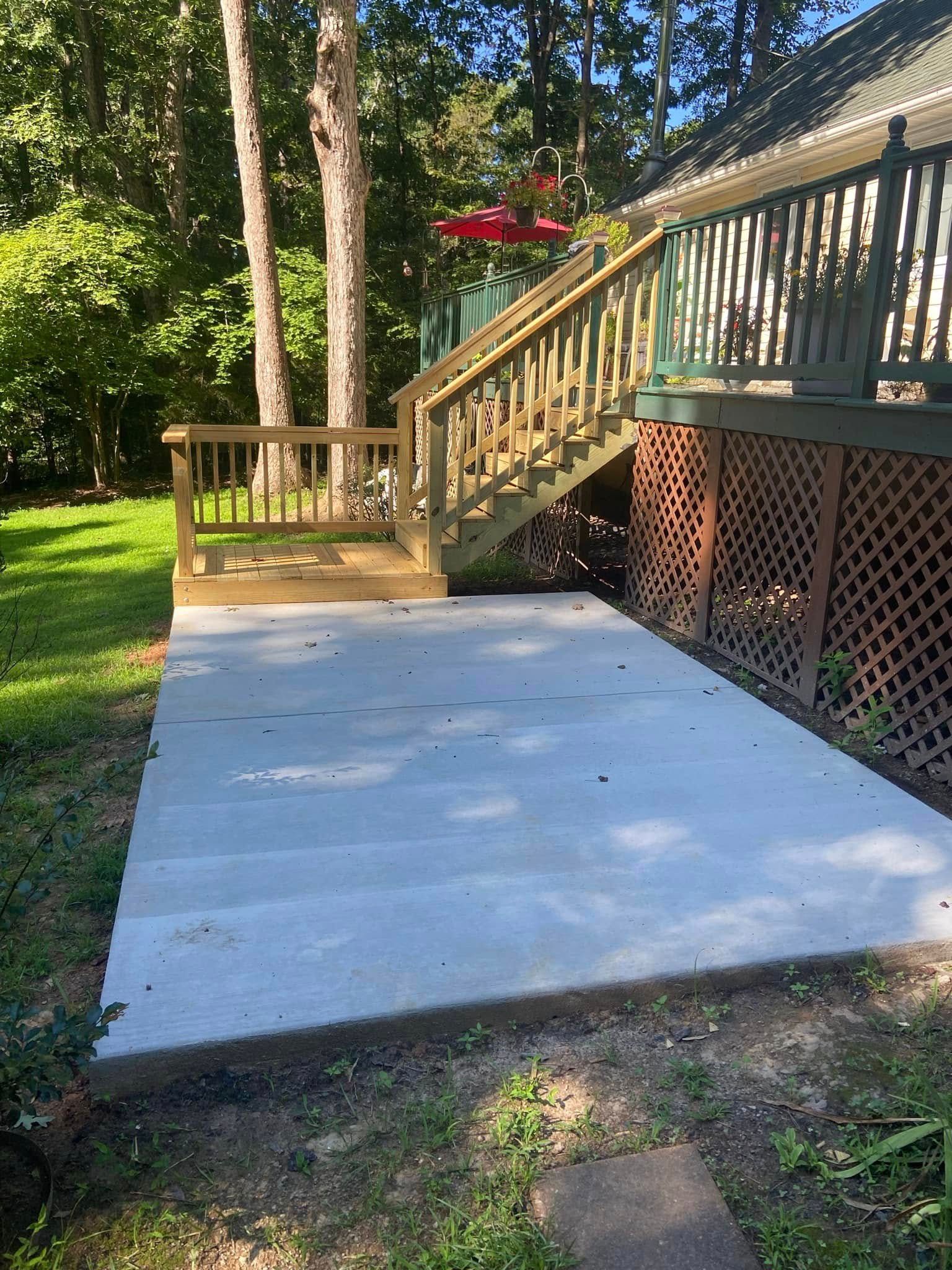 A concrete walkway leading to a wooden deck with stairs.