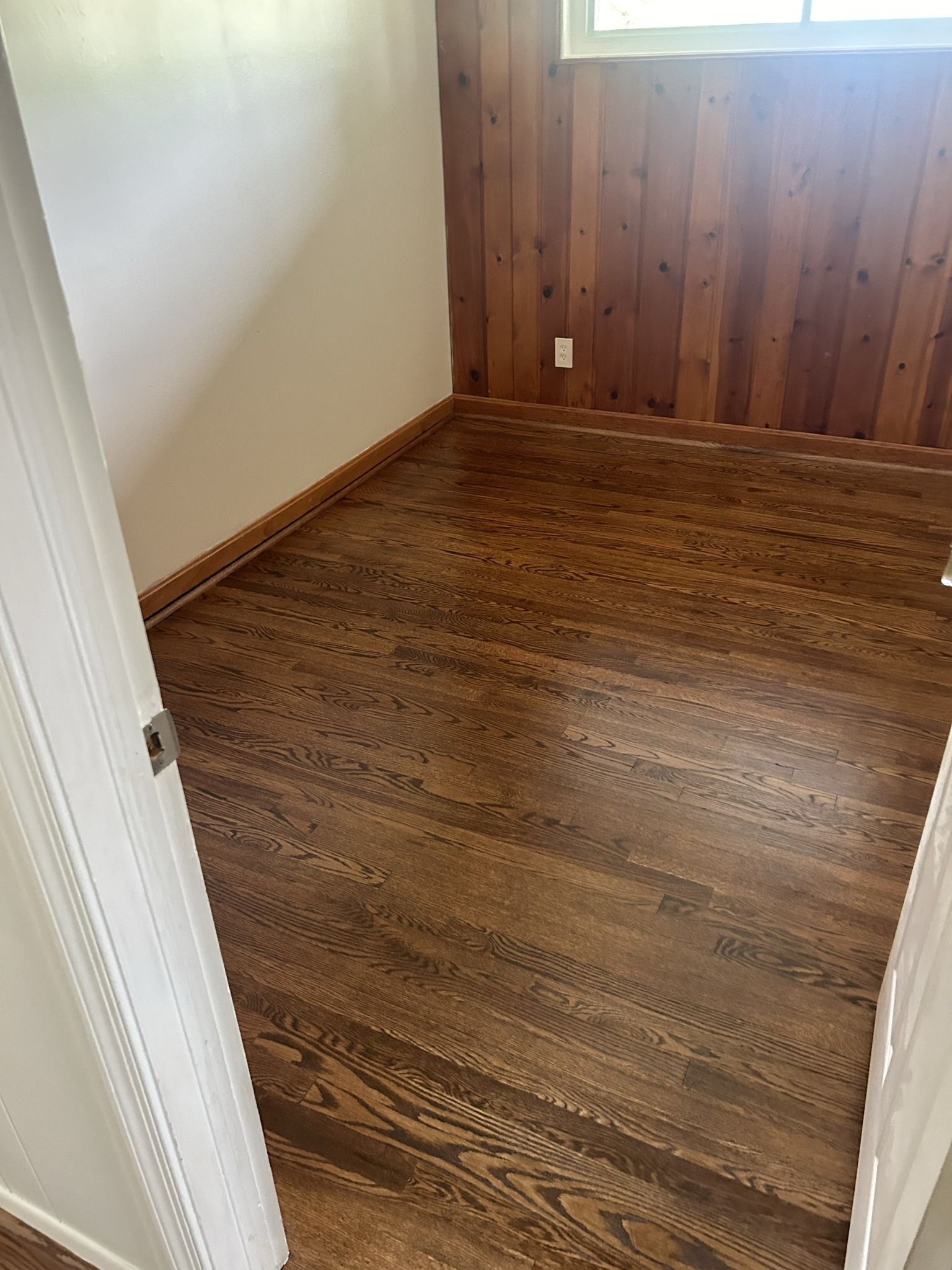A room with hardwood floors and wood paneling on the walls.
