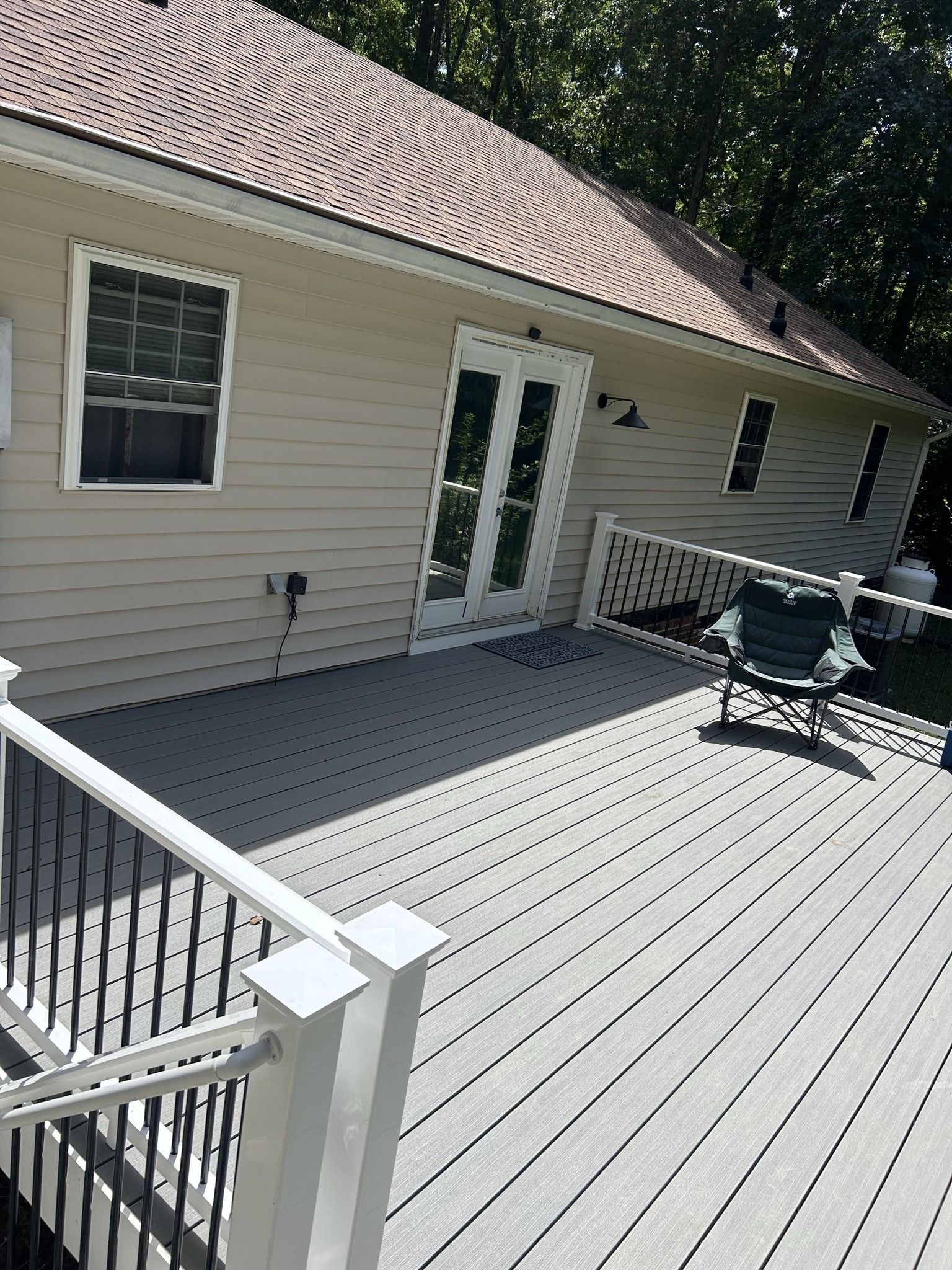 A large deck with a white railing is in front of a house.