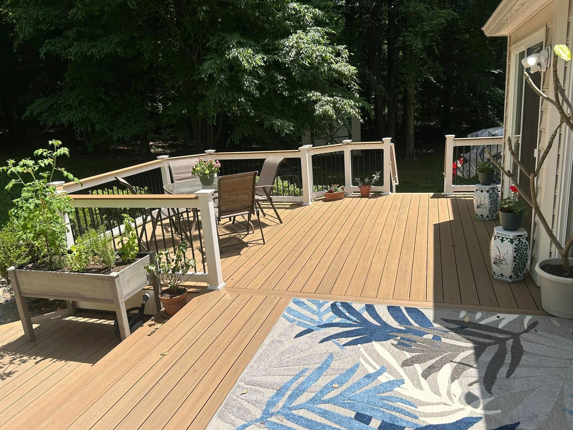 A large wooden deck with a blue rug on the ground.