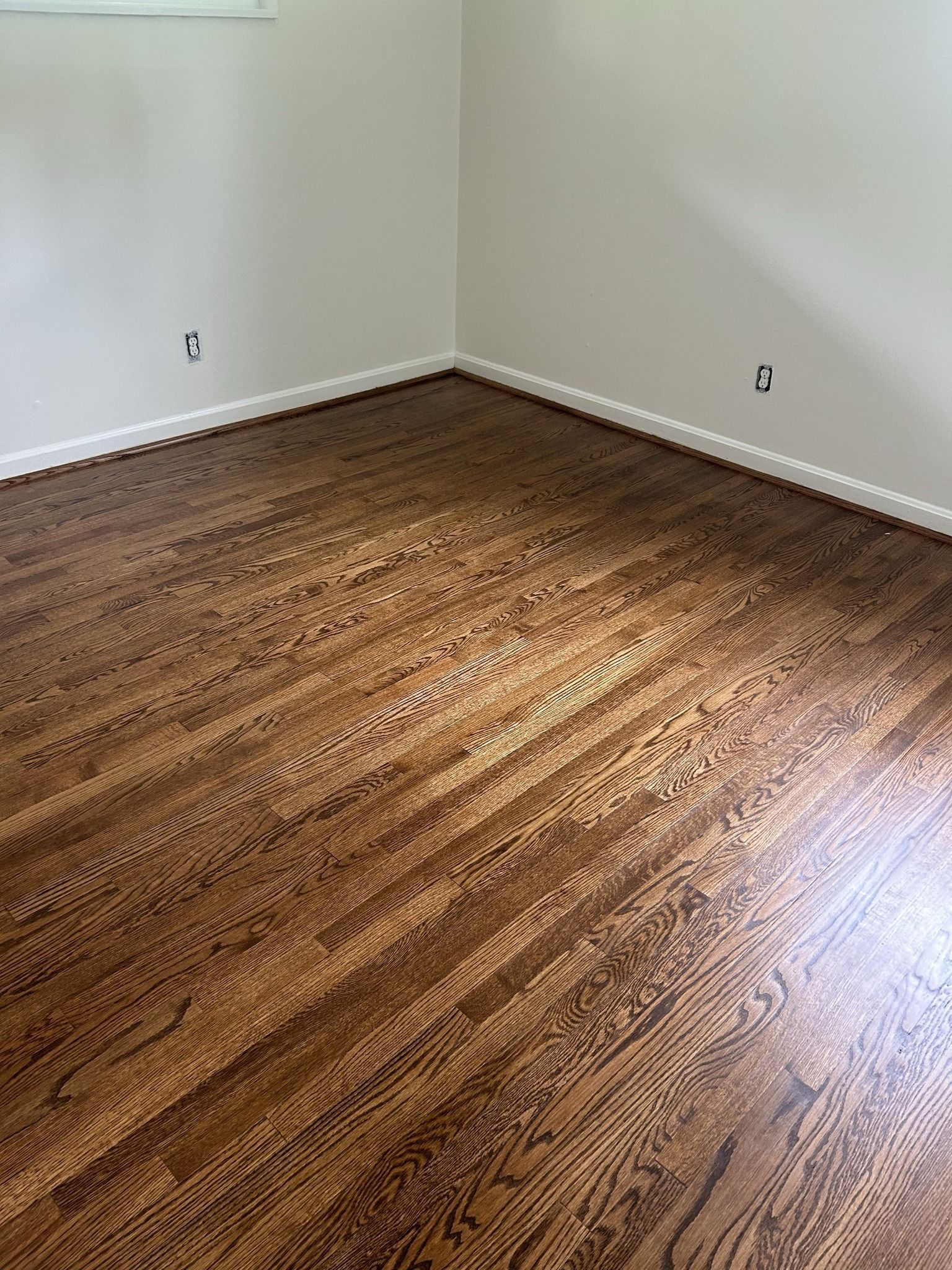 A bedroom with hardwood floors and white walls.