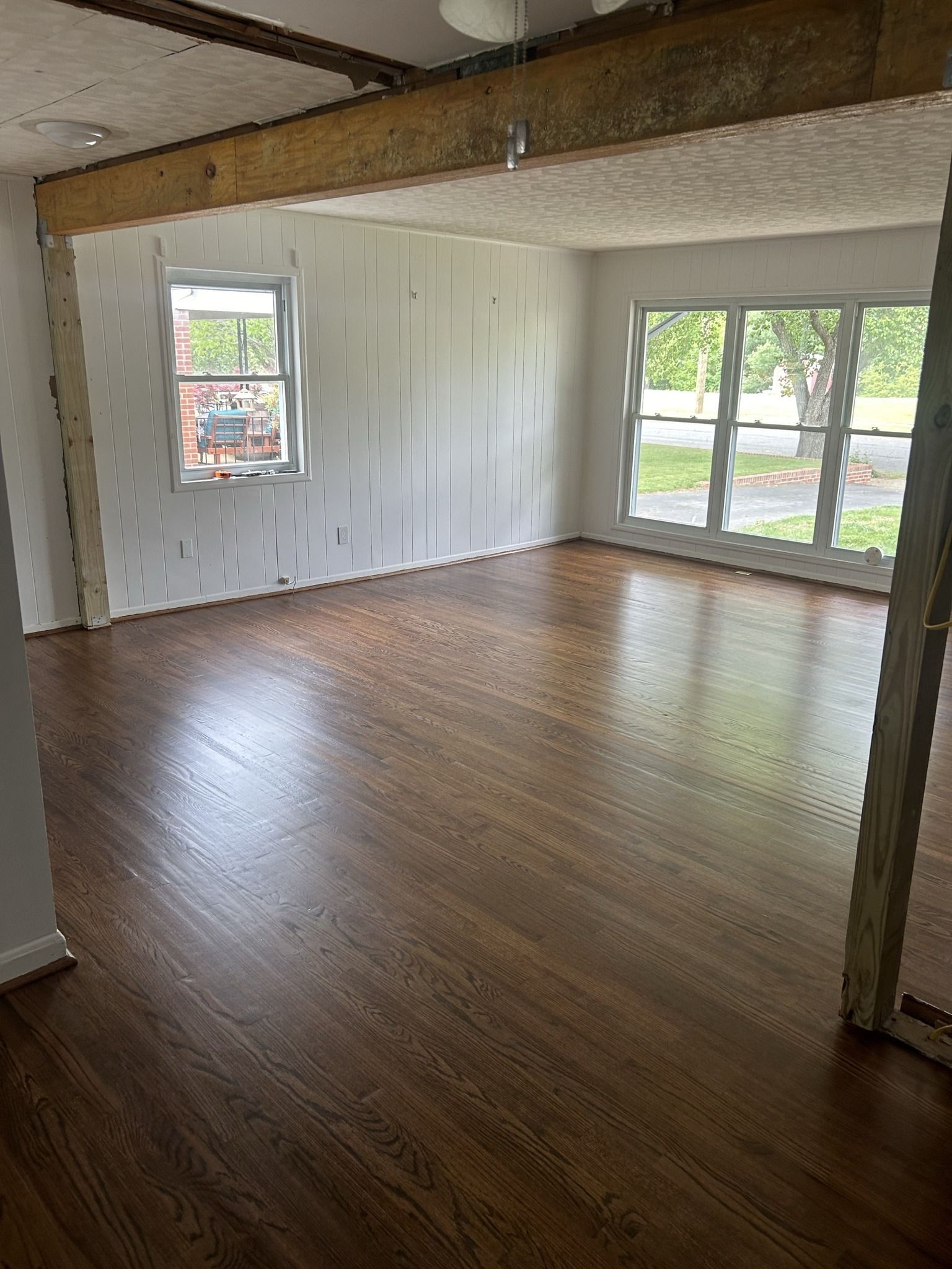 An empty living room with hardwood floors and white walls.
