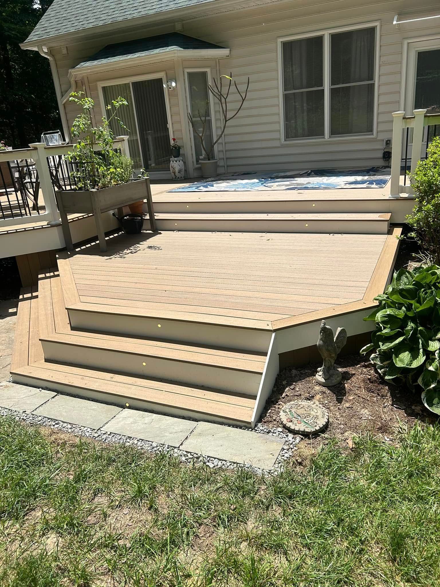 A wooden deck with stairs leading up to it in front of a house.