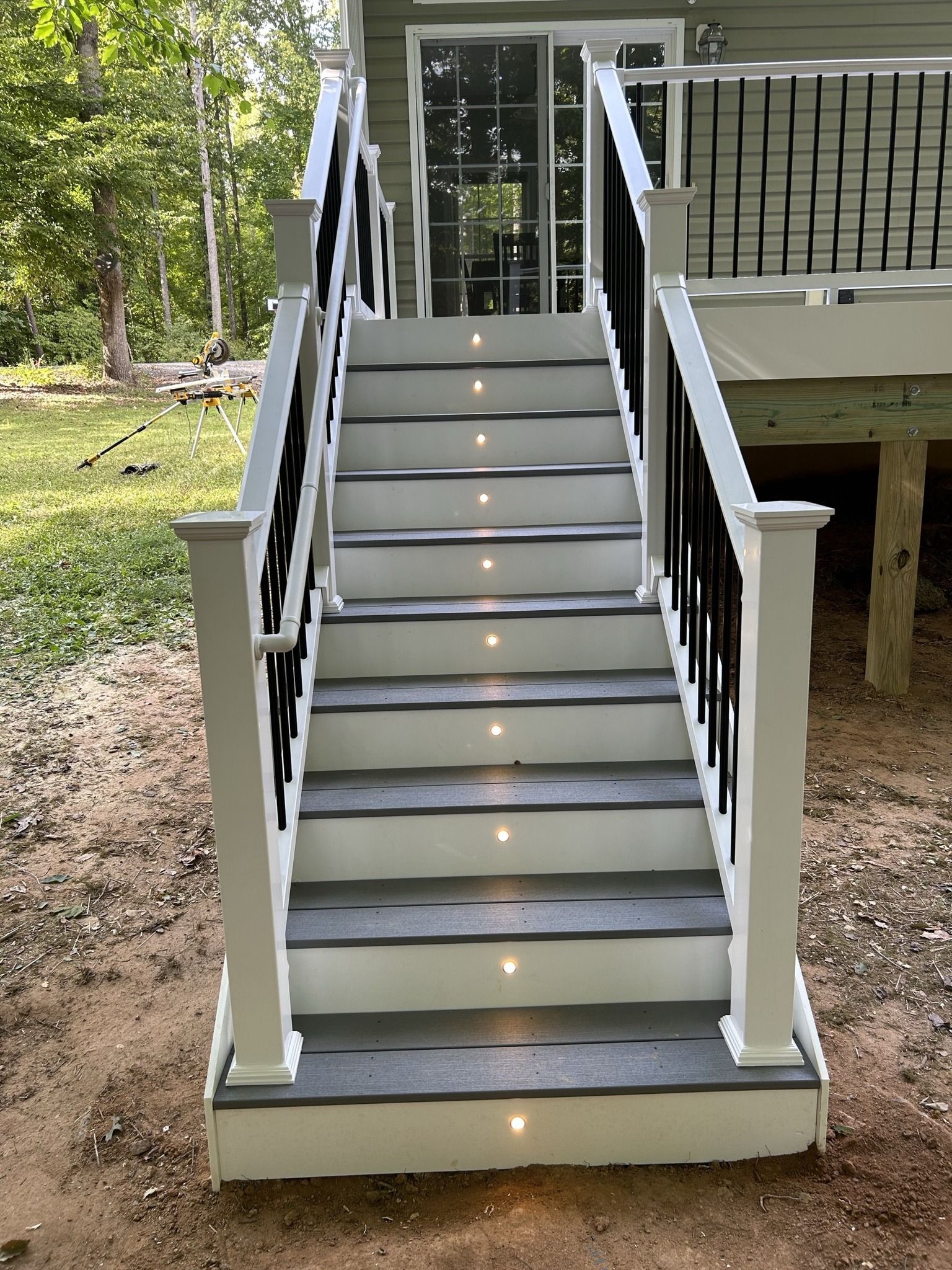 A set of stairs leading up to a deck with lights on the steps.