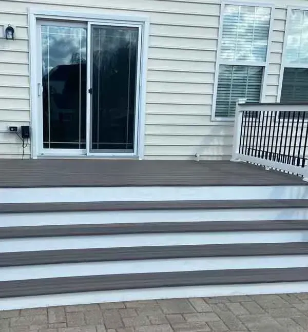There is a deck with stairs leading up to it and a sliding glass door.