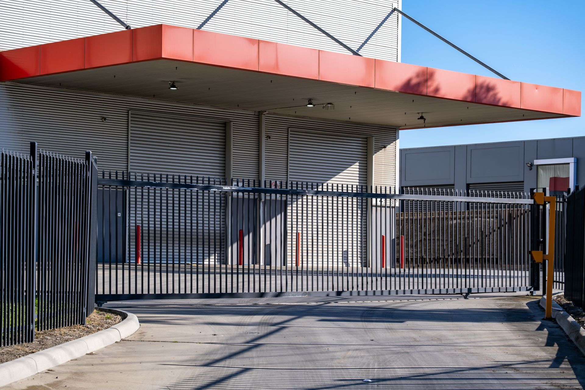 Industrial gate entrance with red canopy and closed metal fence under clear sky
