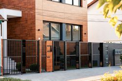 Modern brick house with black metal fence and gate along a paved driveway