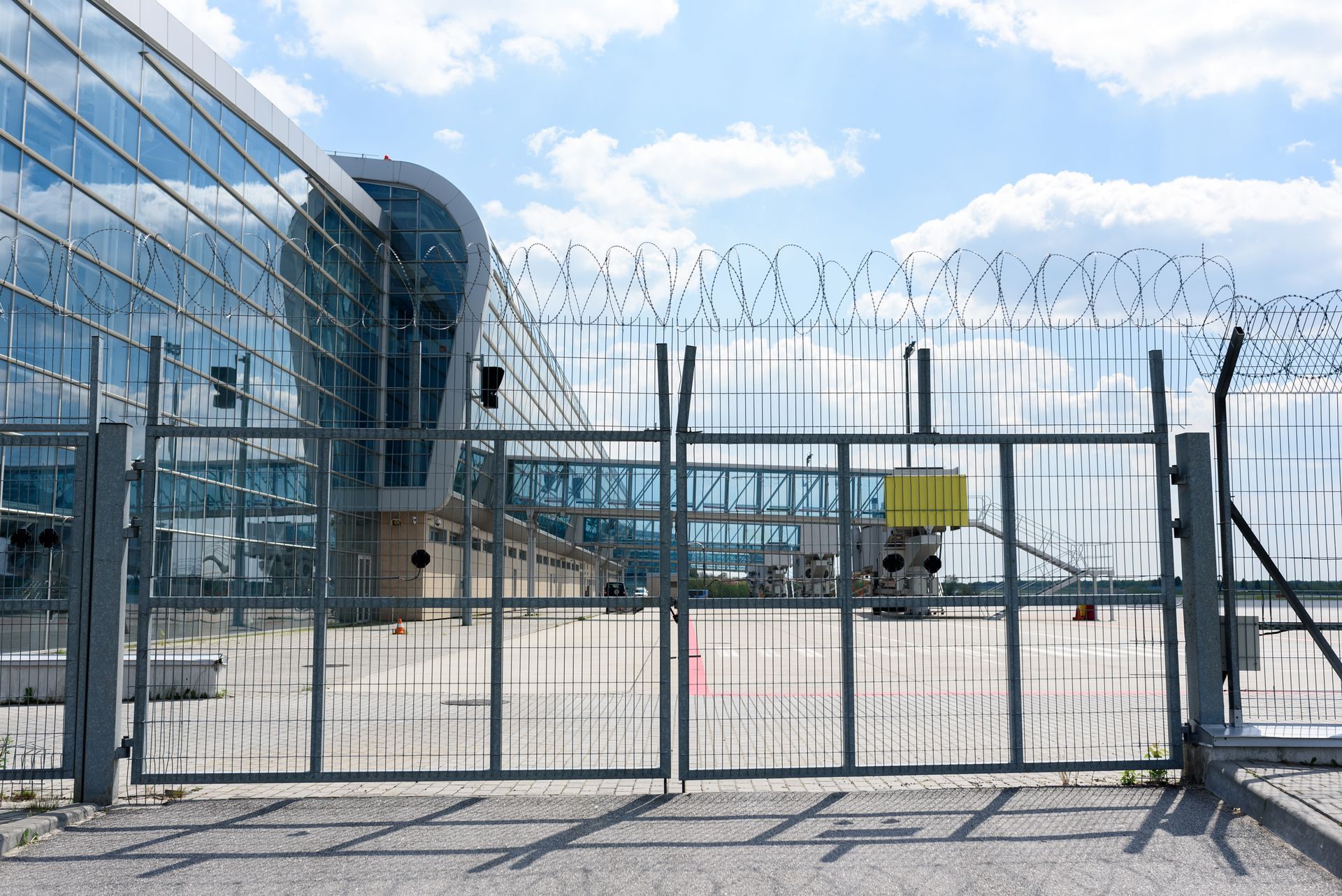 Airport terminal behind a high security fence under a blue sky