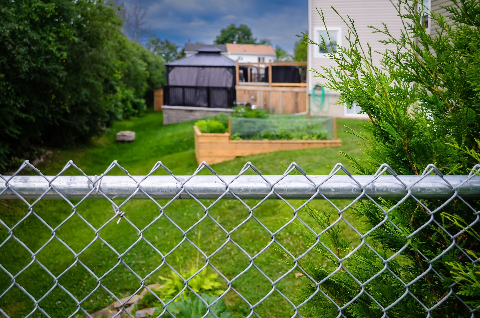 Person pressure-washes a wooden fence with a spray wand.