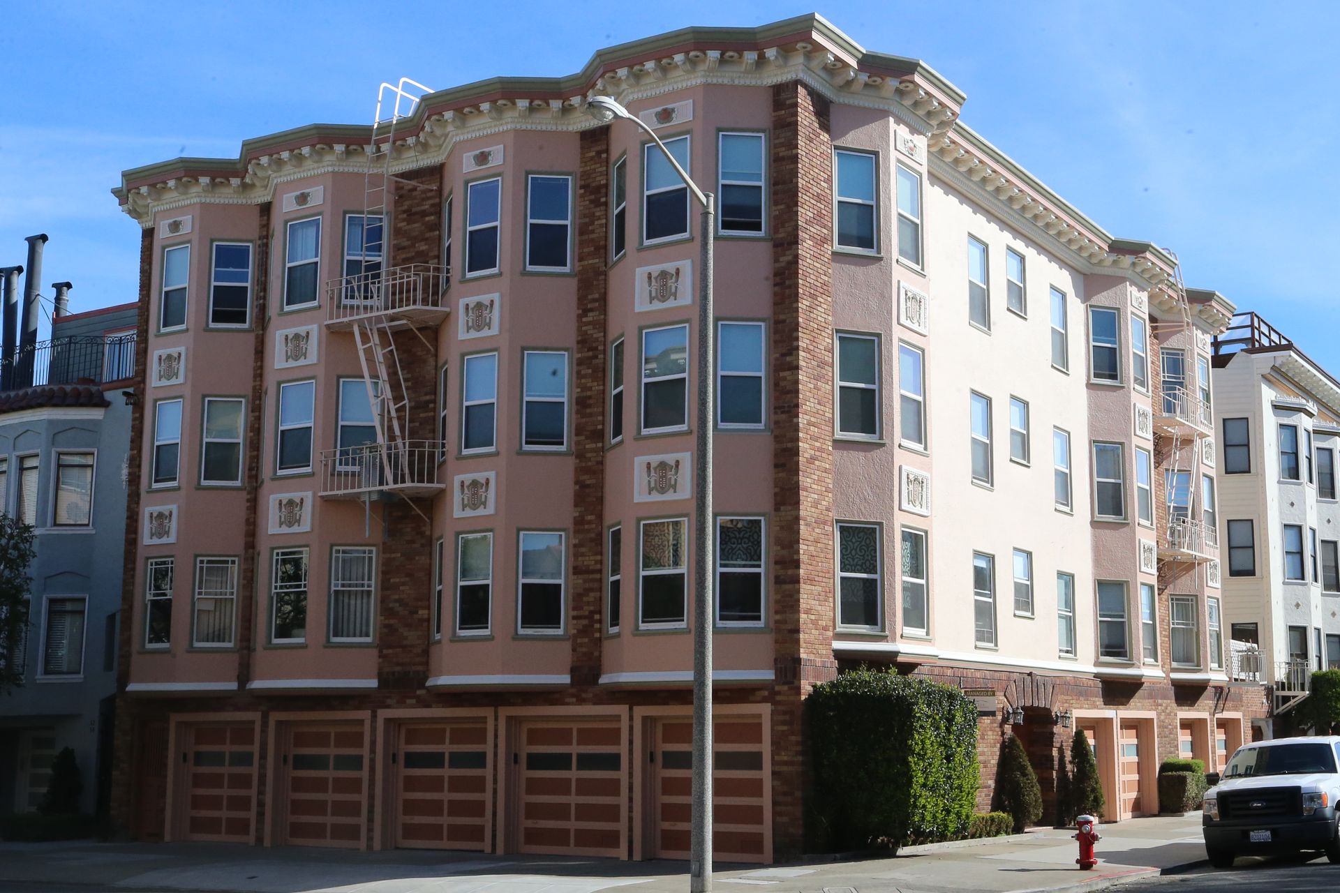 Corner apartment building with red brick and beige stucco under a clear blue sky