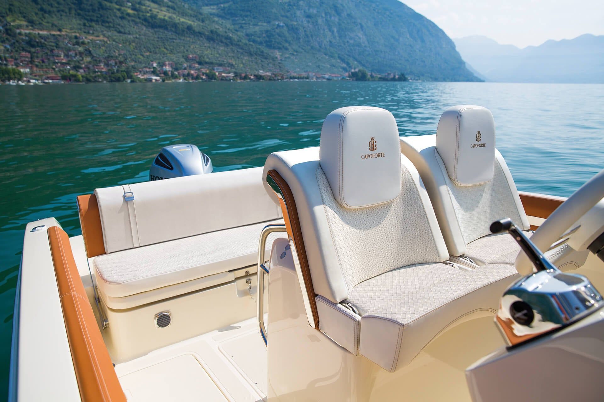 Assentos de luxo em um barco em um lago turquesa com montanhas ao fundo.