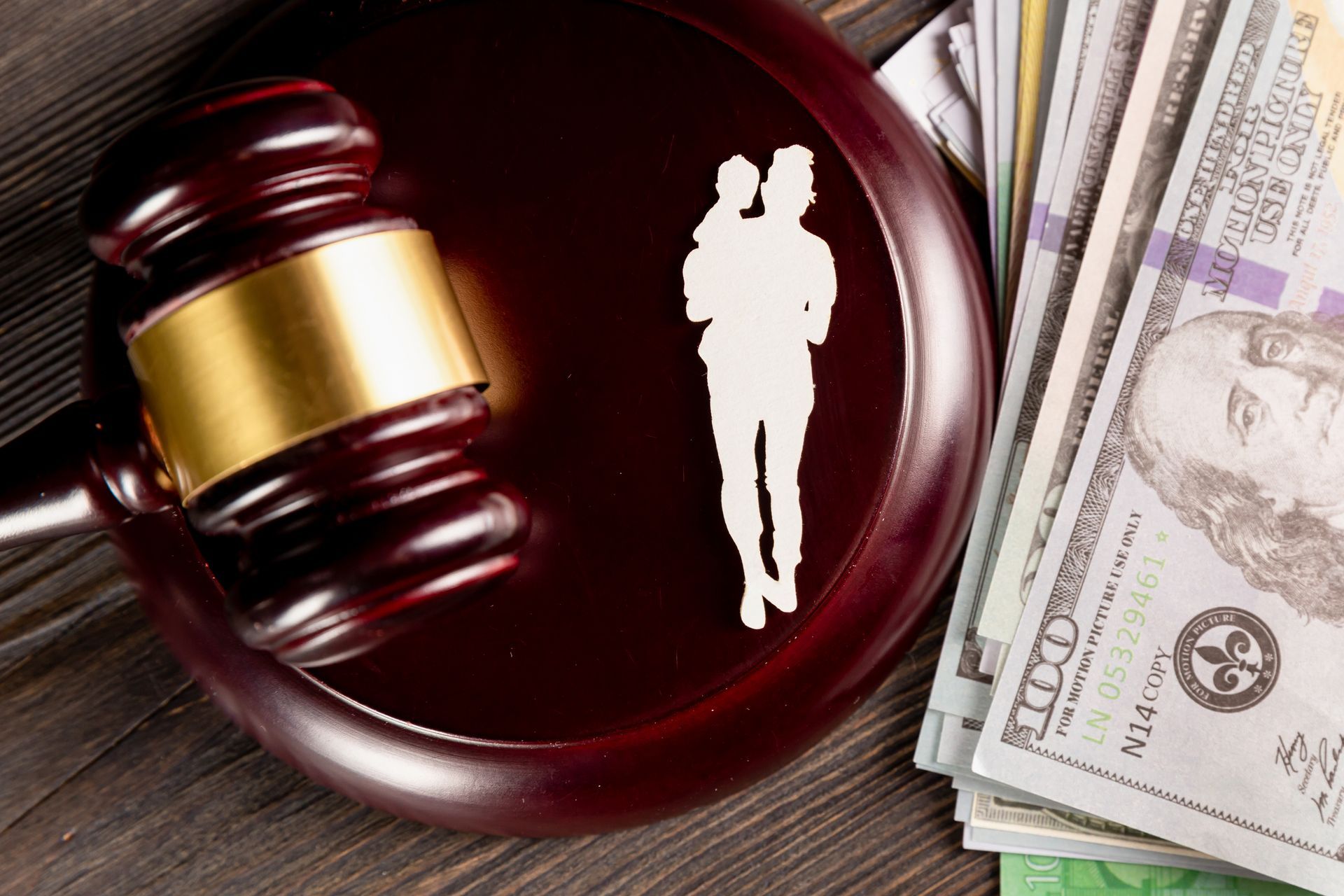 Judge’s gavel beside a silhouette on a courtroom desk with cash, suggesting legal settlement or compensation