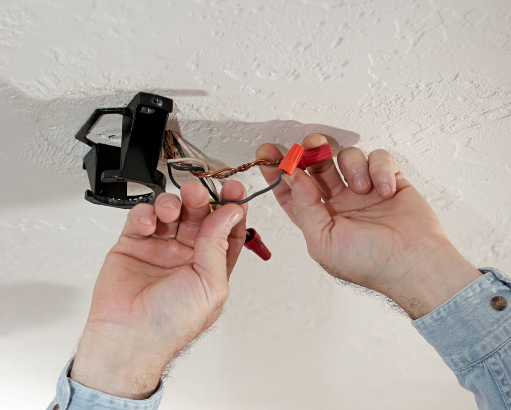 Person Connecting Electrical Wires With Wire Connectors Near a Ceiling Light Fixture — Carl Voss Electrical In Urangan, QLD