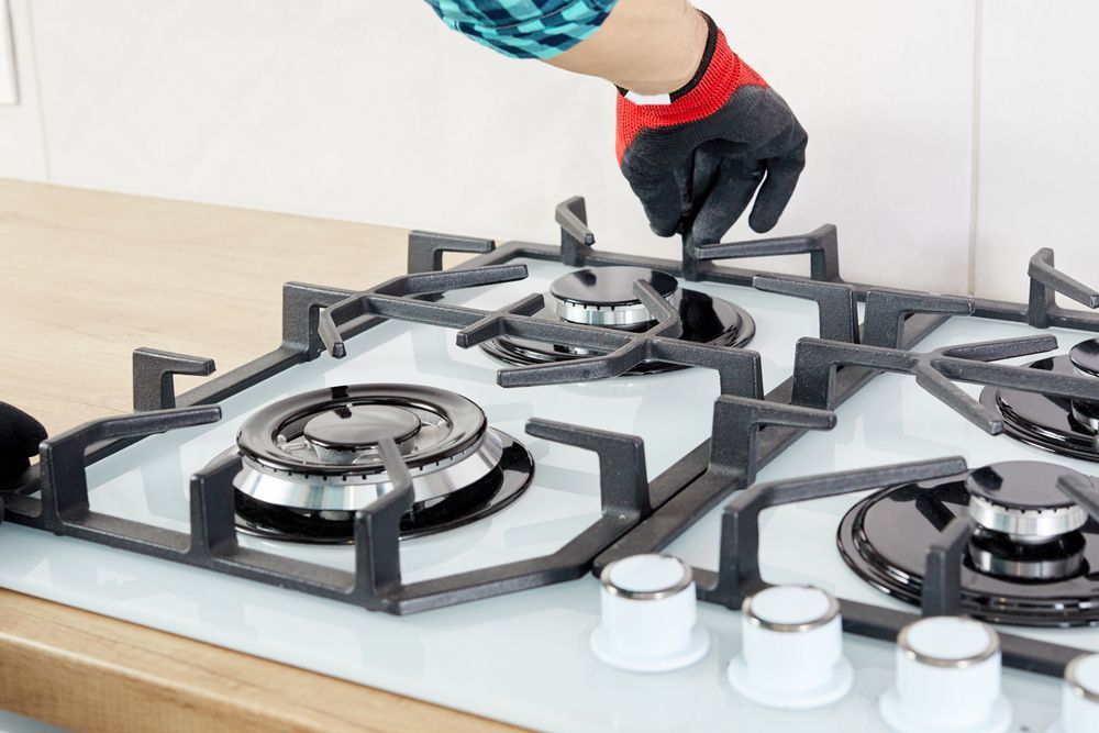 Person Wearing a Glove, Installing a Gas Stove Top — Carl Voss Electrical In Urangan, QLD