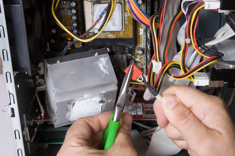 Person Using Pliers to Cut a Wire Inside a Computer Tower — Carl Voss-Electrician In Urangan, QLD