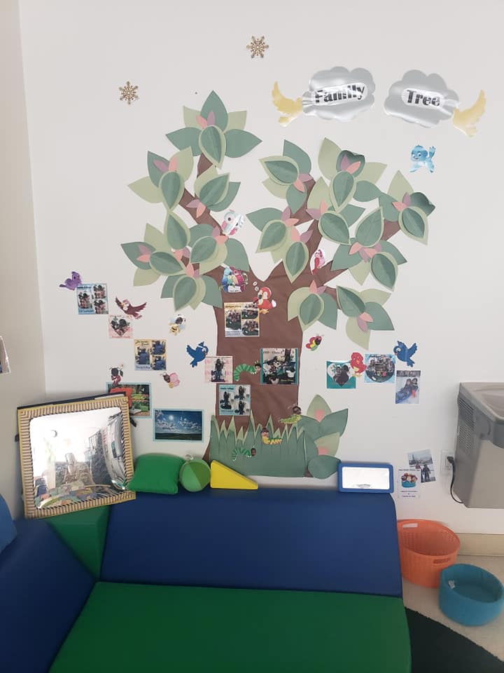 A room with a couch and a tree on the wall