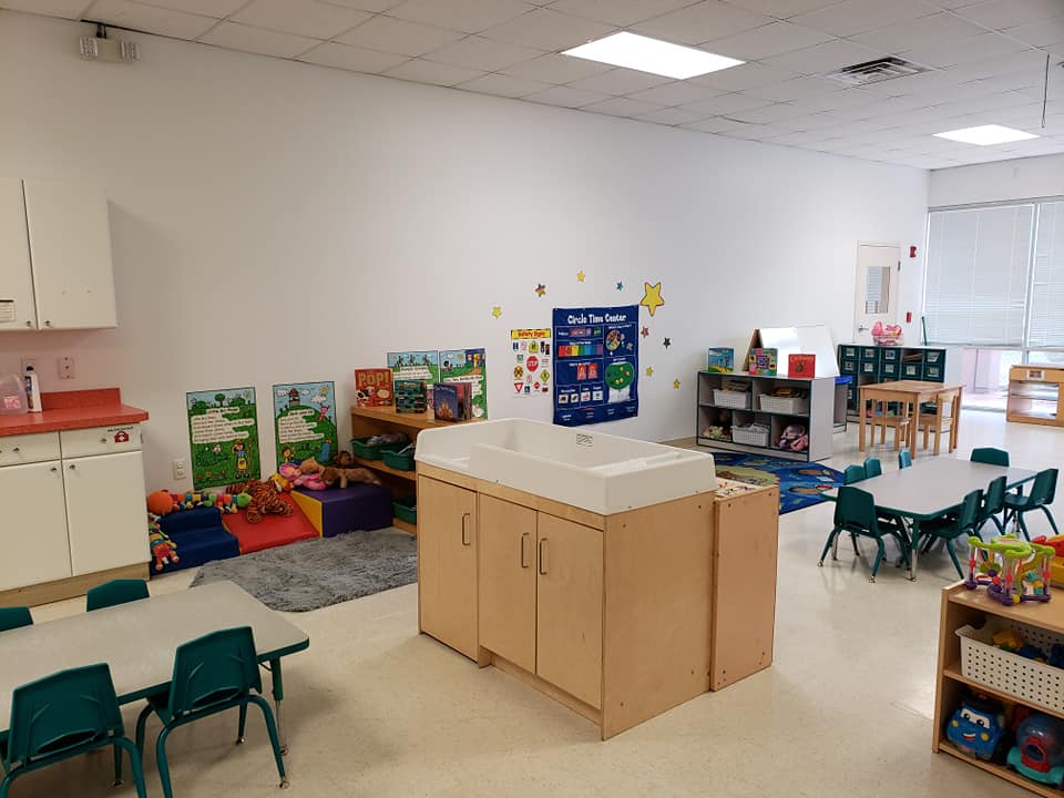 A classroom with tables , chairs , and a sink.