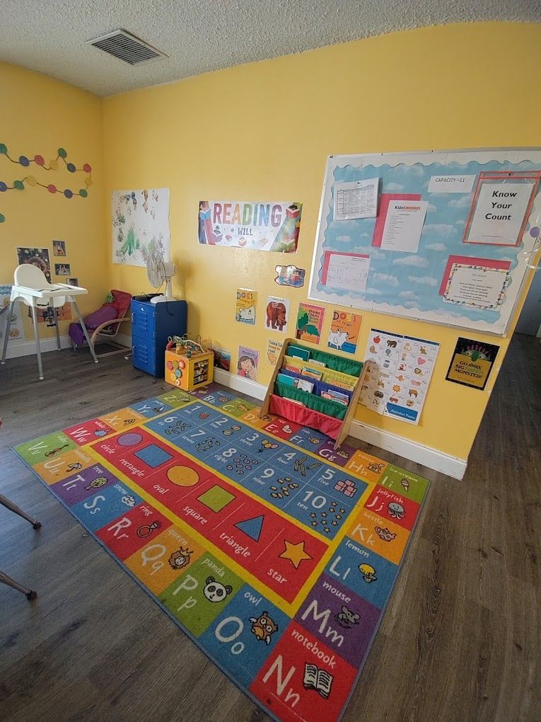 A classroom with yellow walls and a colorful rug on the floor.