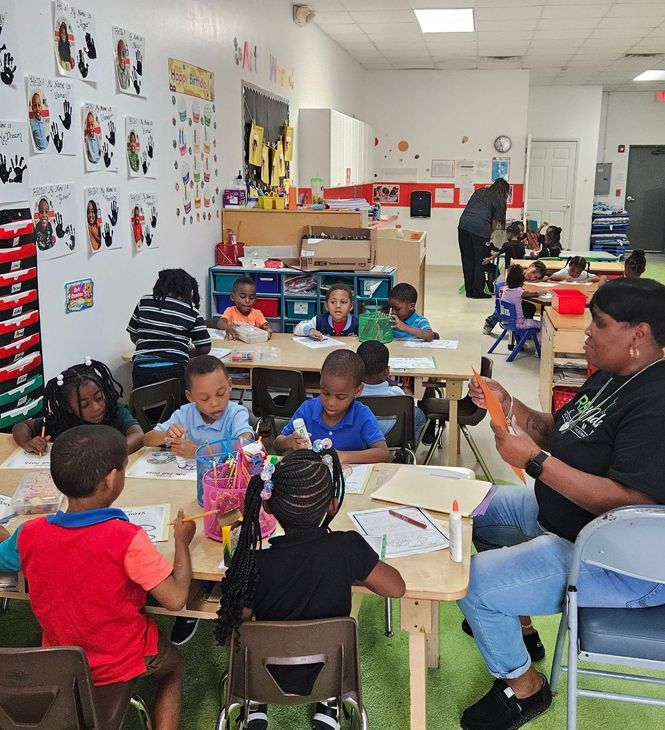 A group of children are sitting at tables in a classroom.