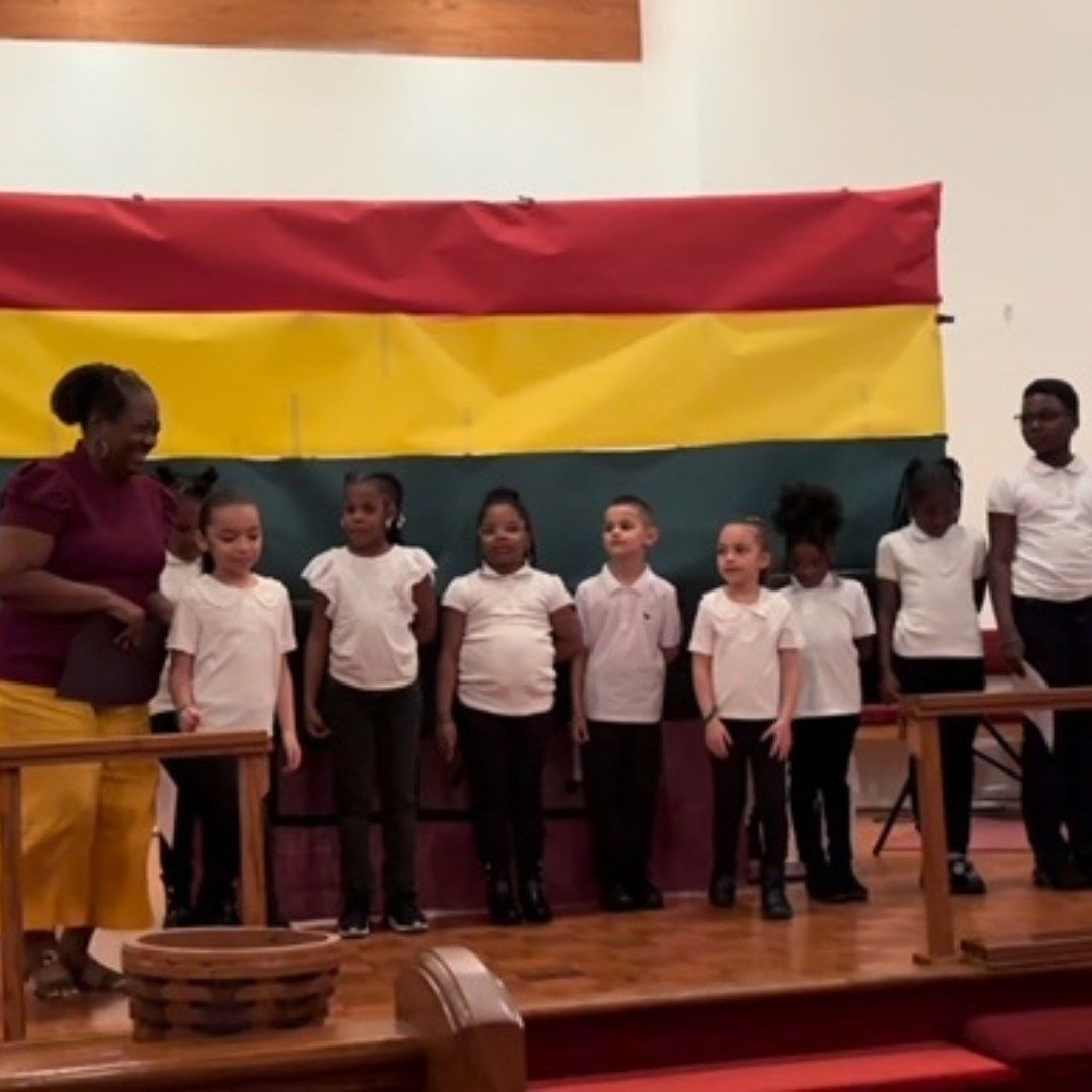 A group of children standing in front of a flag