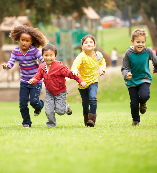 A group of children are running in a park holding hands.