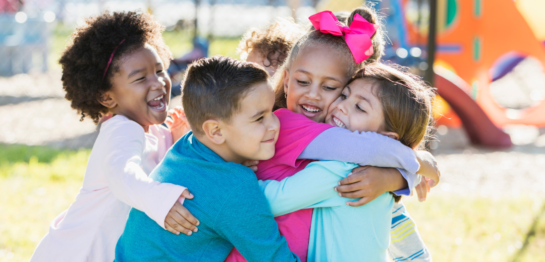 A group of children are hugging each other in a park.