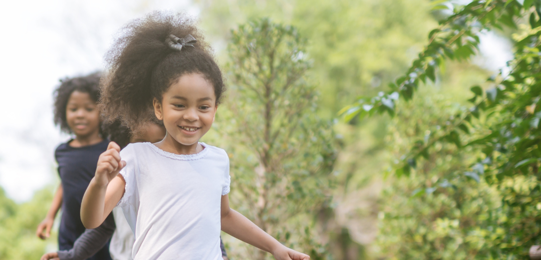 A group of young girls are running through a park.