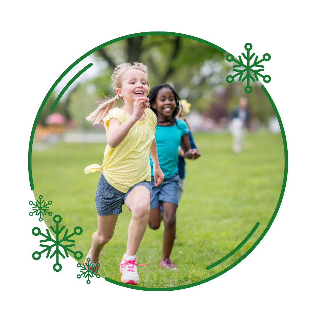 Two little girls are running in the grass in a park.