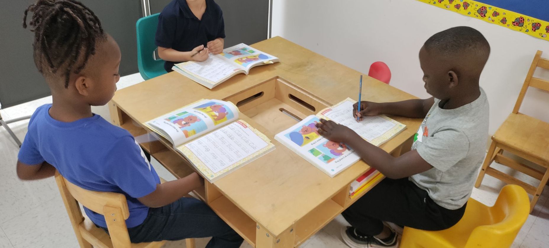 A group of children are sitting at a table in a classroom.