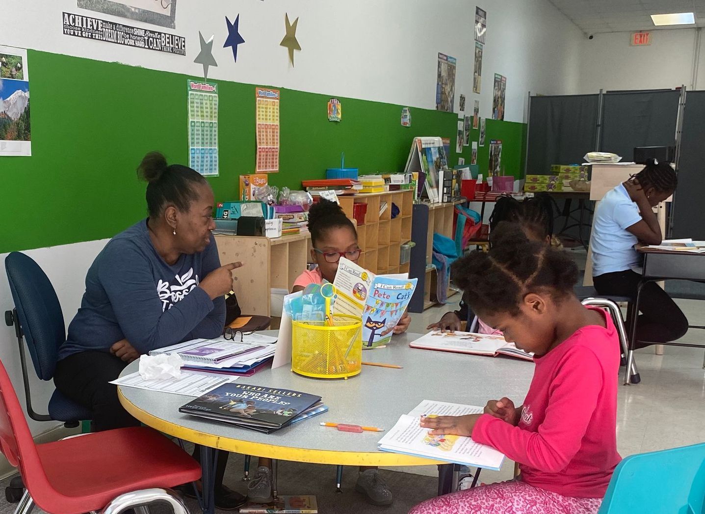 A group of children are sitting around a table reading books.