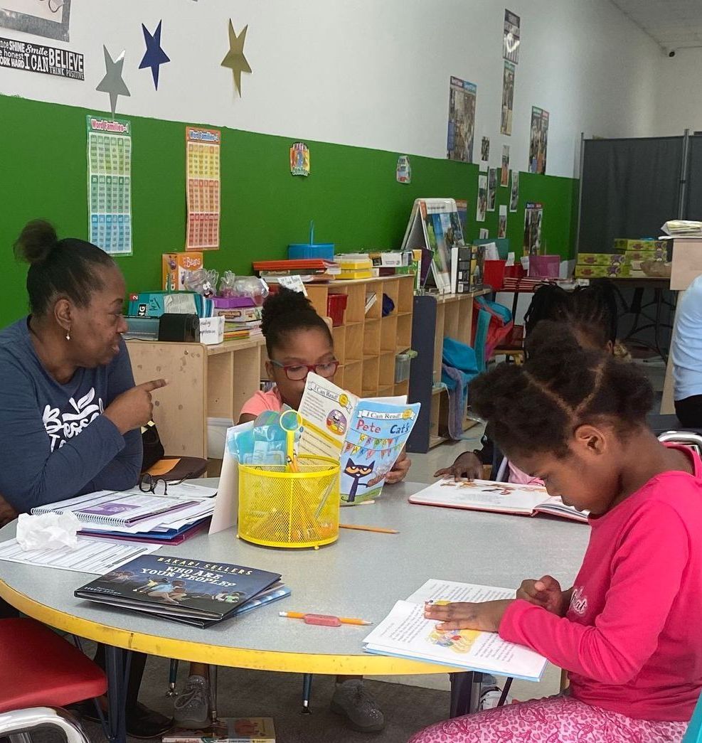 A group of children are sitting around a table reading books