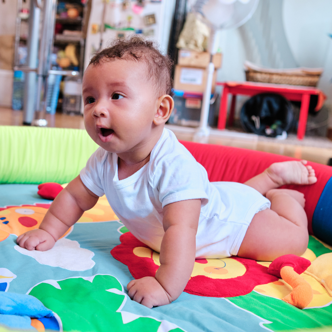 A baby is crawling on a colorful mat.