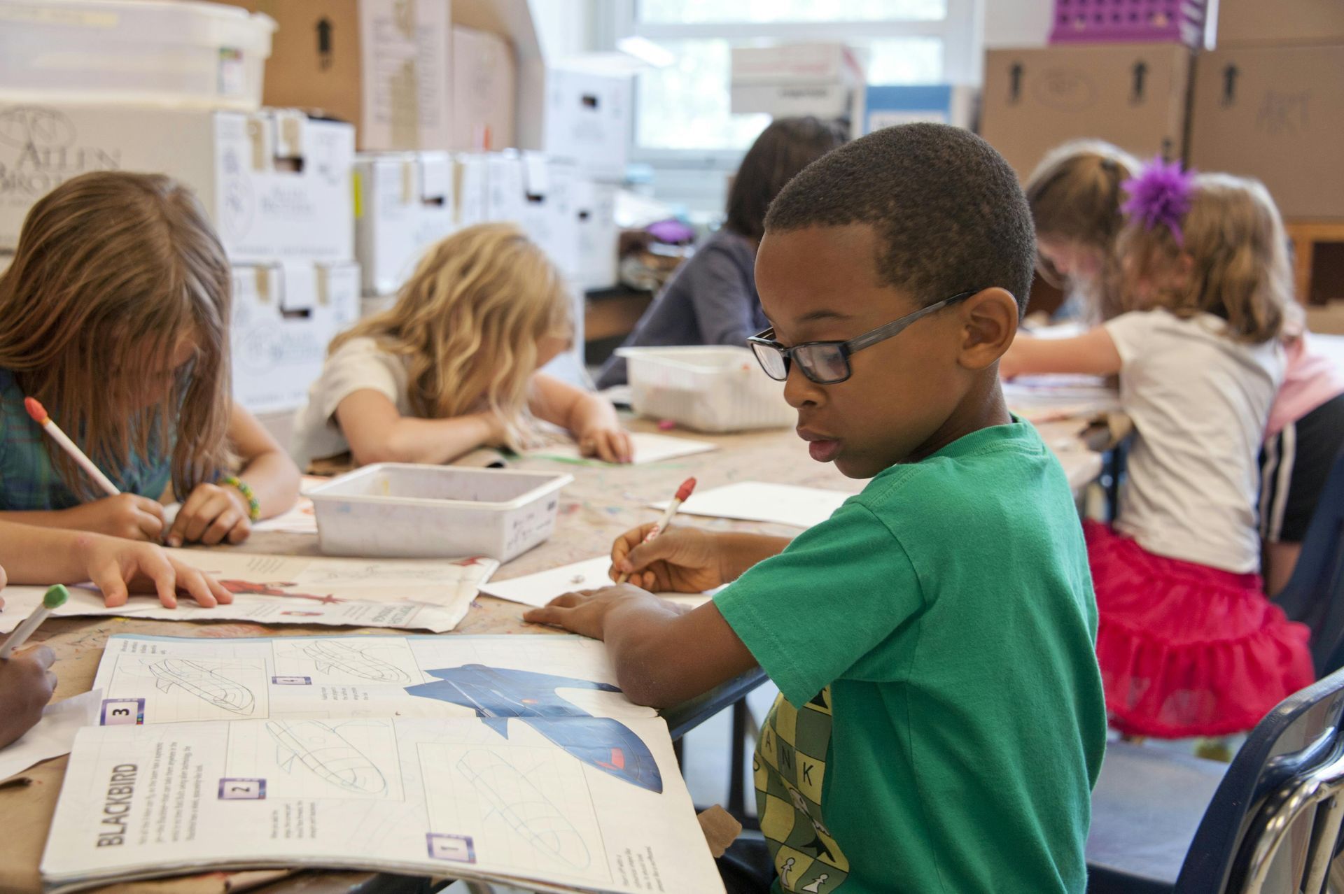 A group of children are sitting at a table in a classroom.