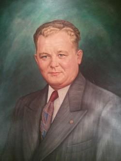 Studio portrait of a man in a gray suit and tie against a dark green background