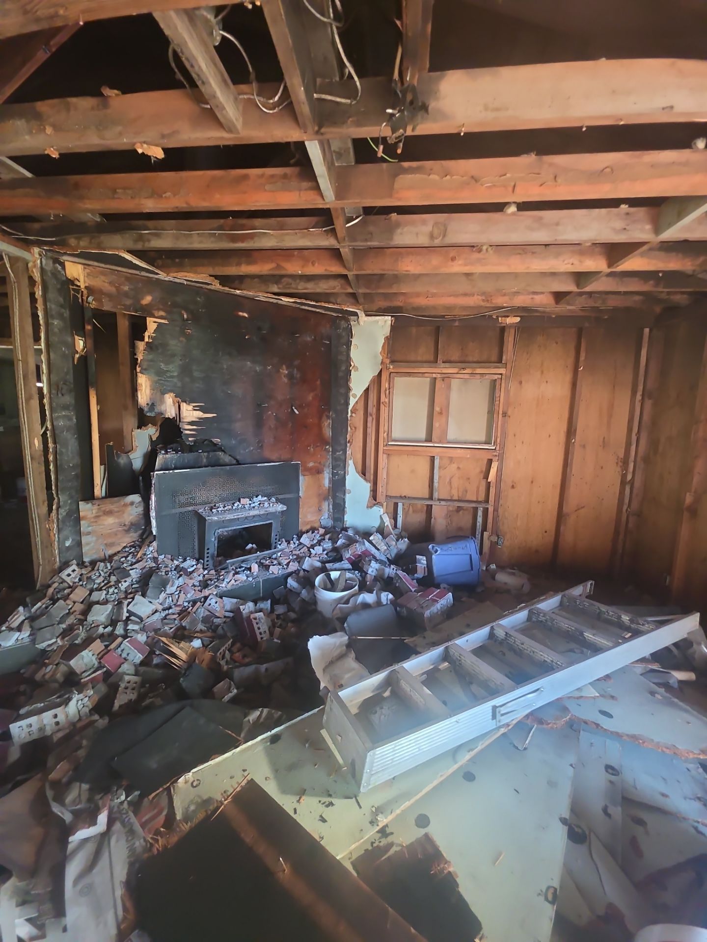 Fire-damaged room with collapsed ceiling, charred walls, and debris scattered across the floor