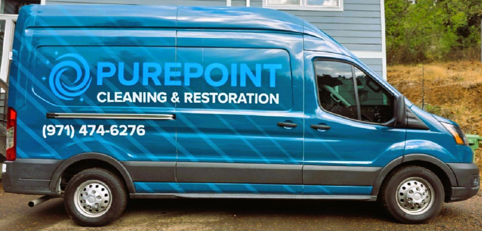 Blue PurePoint Cleaning & Restoration van parked outdoors, with company logo and phone number on the side