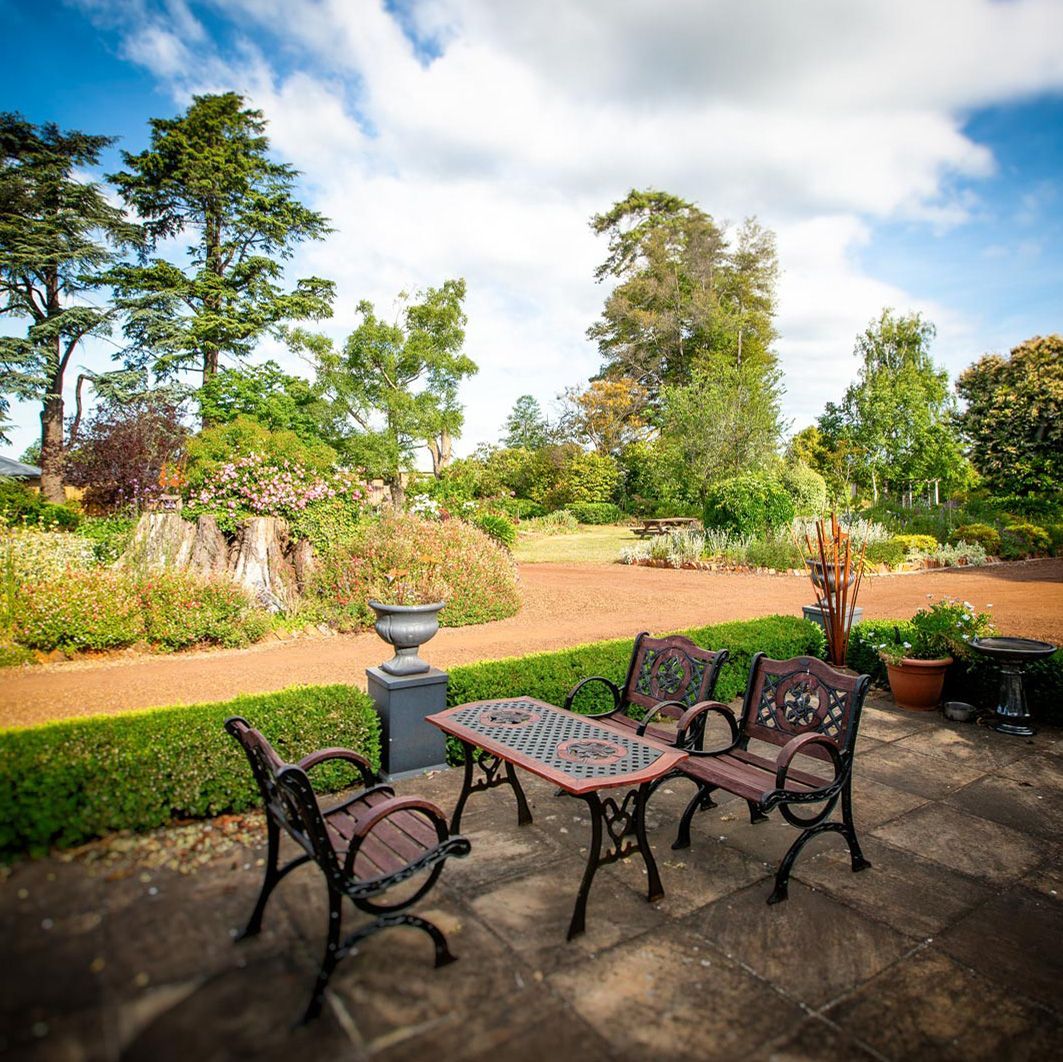 A table and chairs are sitting on the patio in the garden.